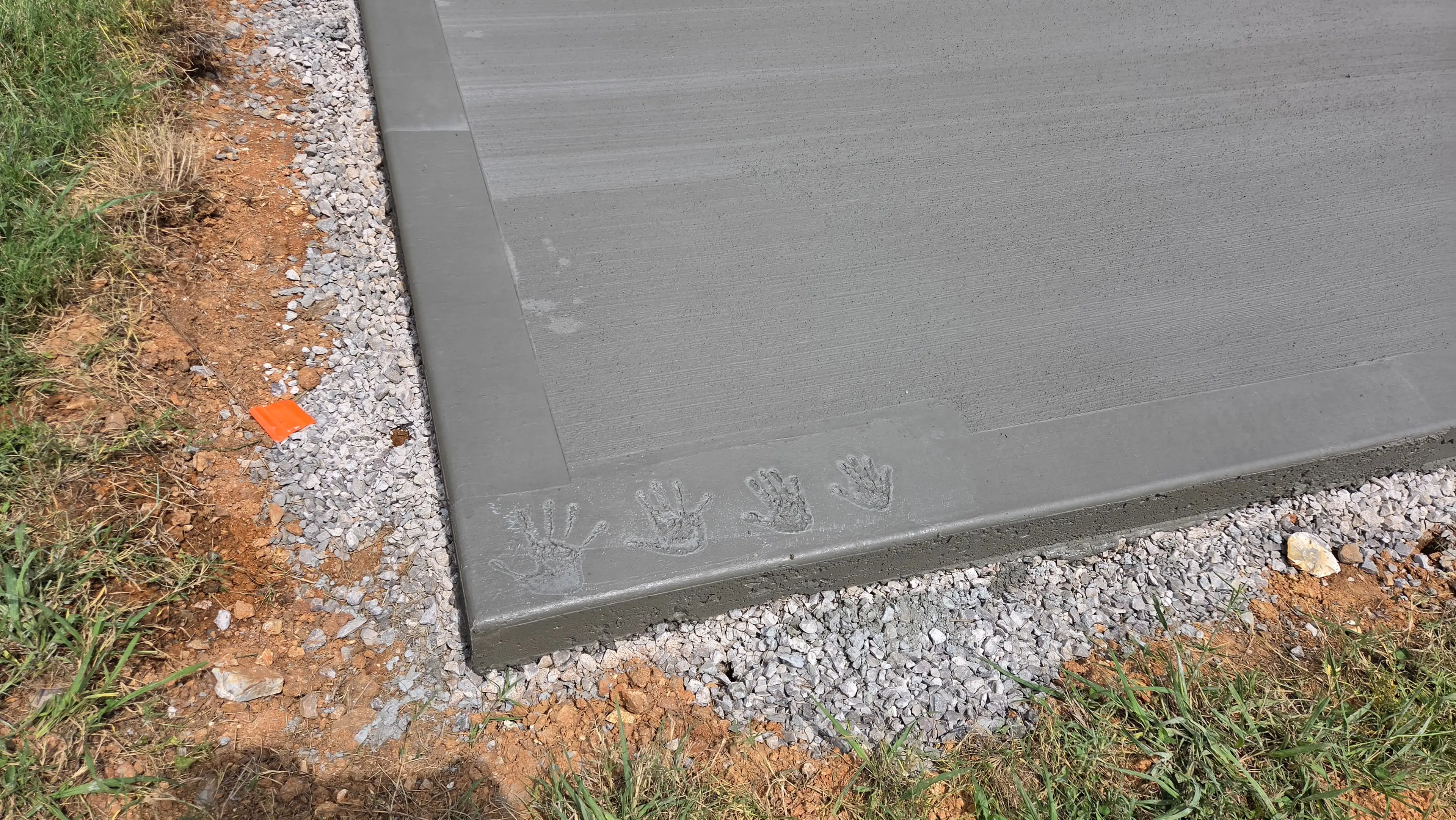 Handprints pressed into fresh concrete pad edge