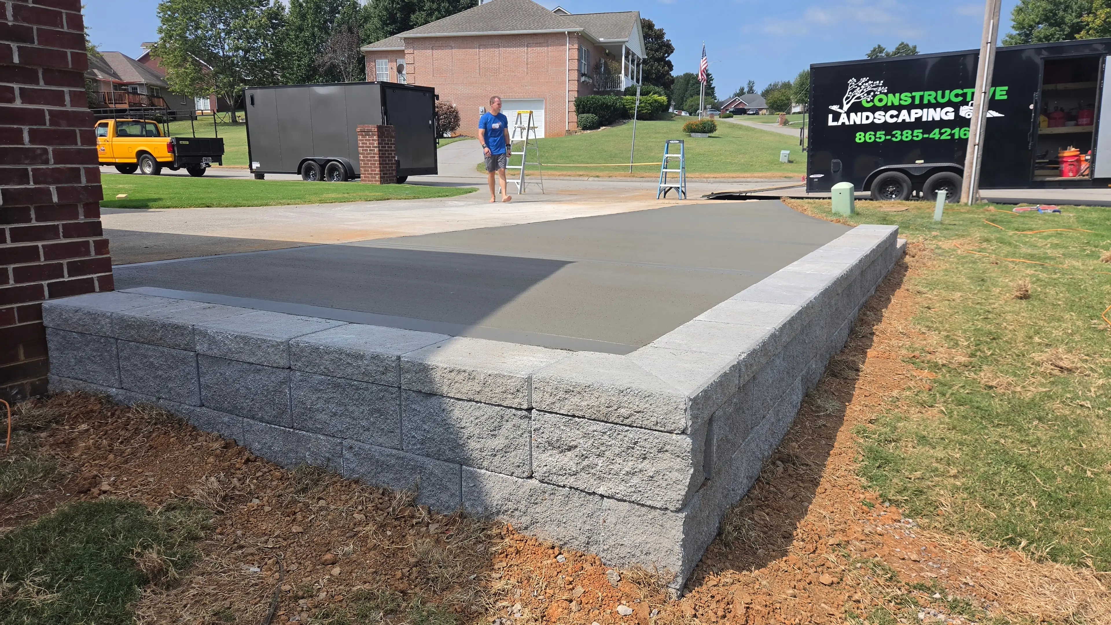 Fresh concrete pad with granite block retaining wall