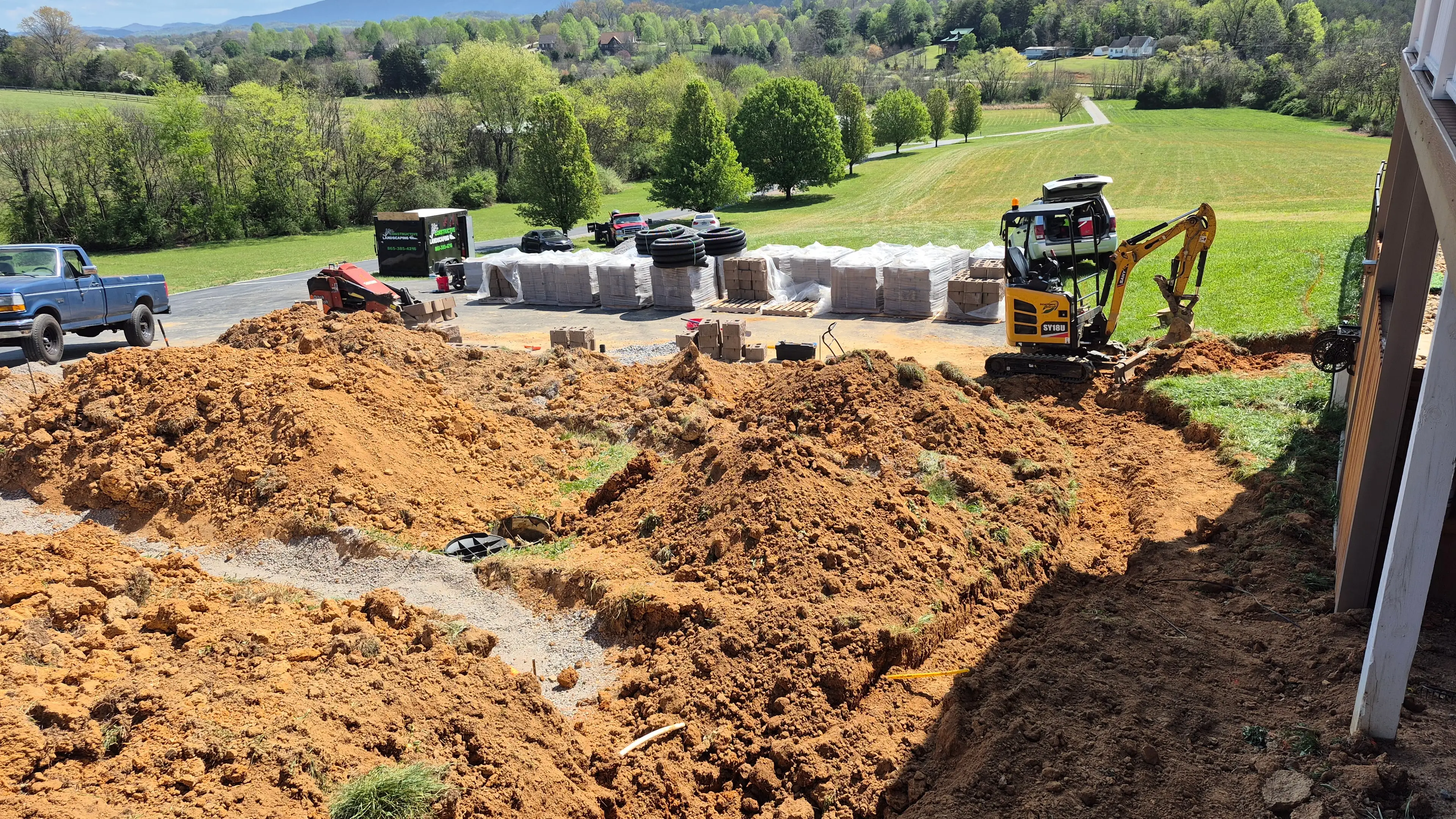 Mini excavator and materials staged for large retaining wall project