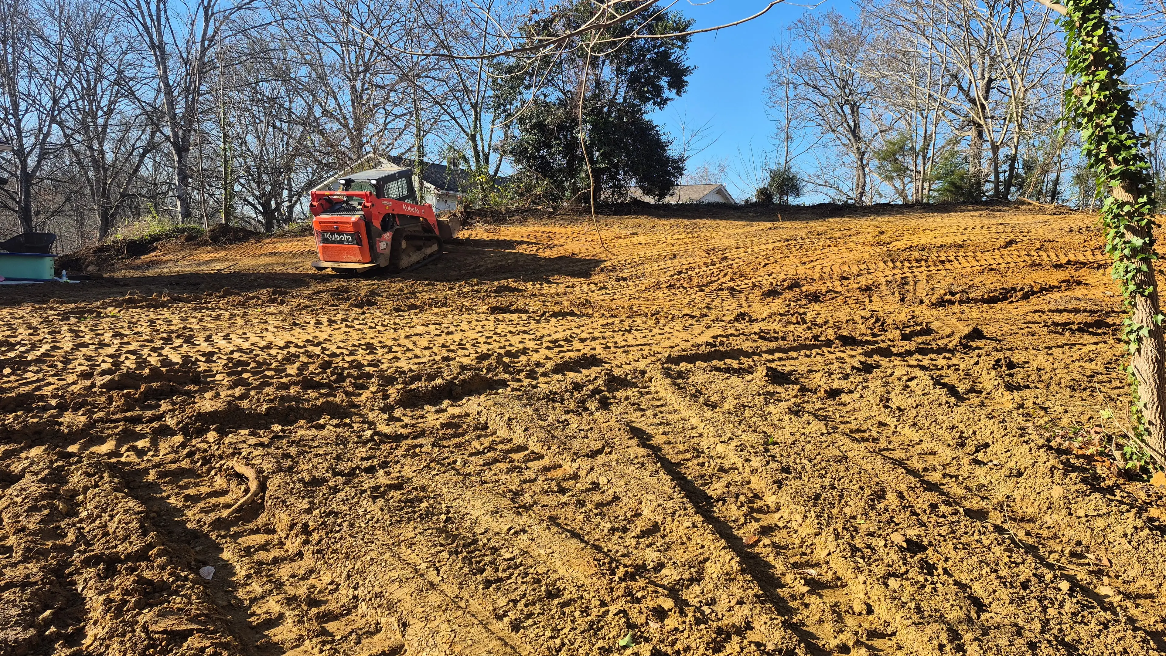 Skid steer grading and clearing a large yard