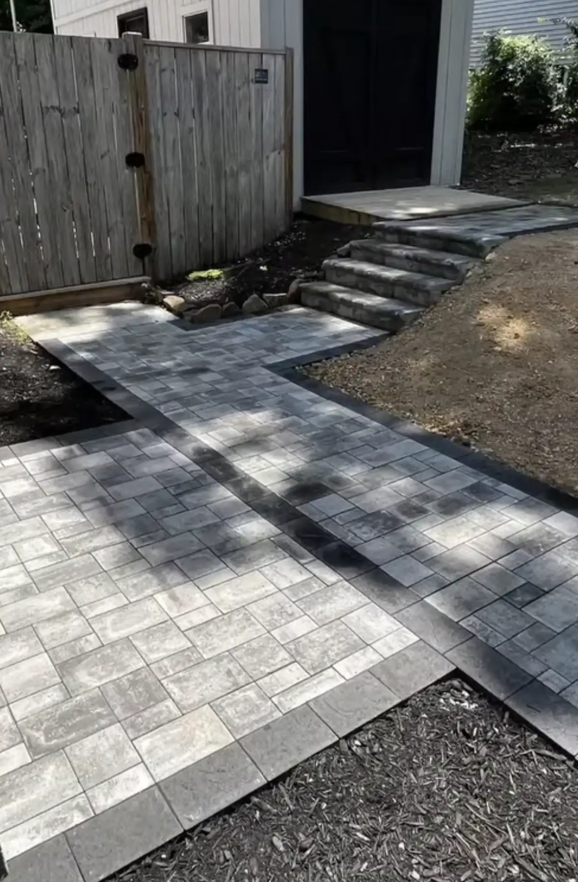 Paver patio with decorative border, gate, and stone steps