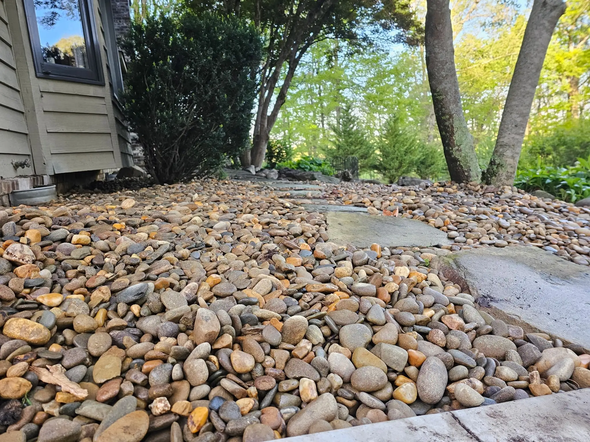River rock ground cover with concrete stepping path along home exterior