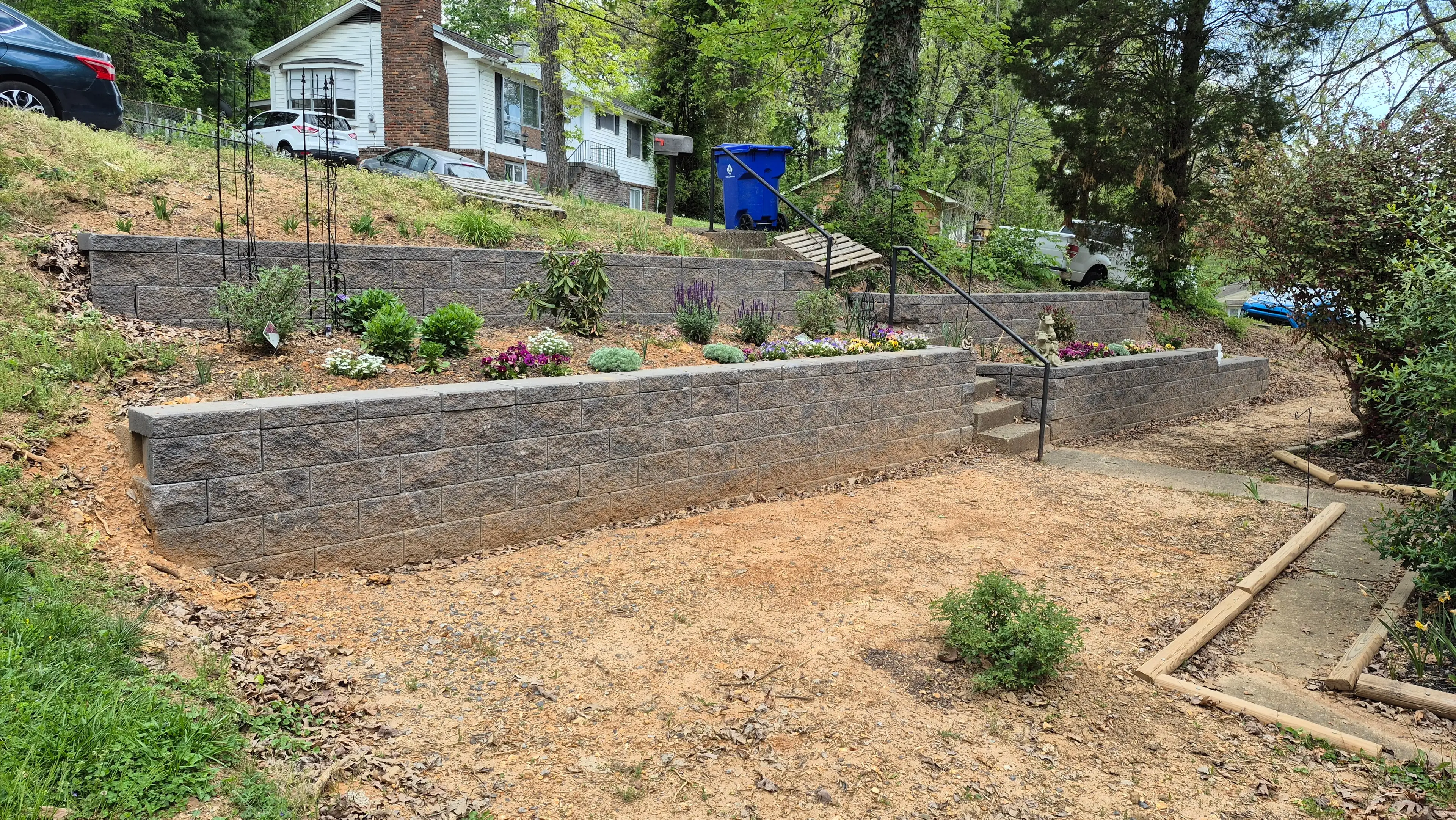 Tiered block retaining walls with flowering garden beds and steps